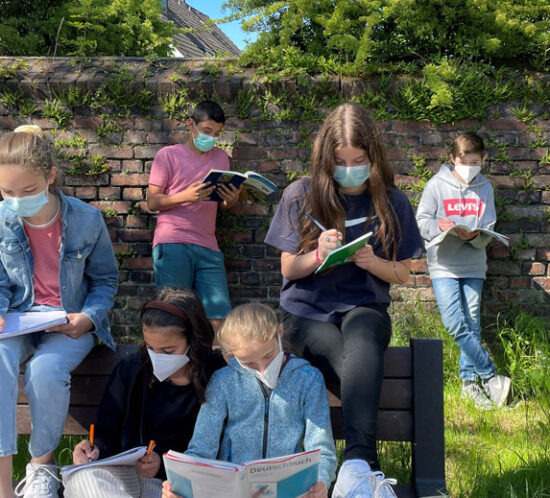 Schüler sitzen auf einer Bank im Sommer und lernen