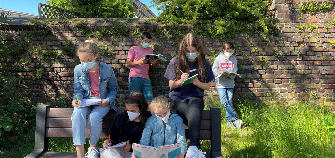 Schüler sitzen auf einer Bank im Sommer und lernen